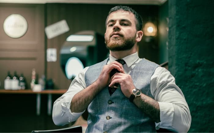 Barber i vest og slips i barberstolen