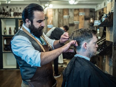 Barber klipper en kunde ved spejlet